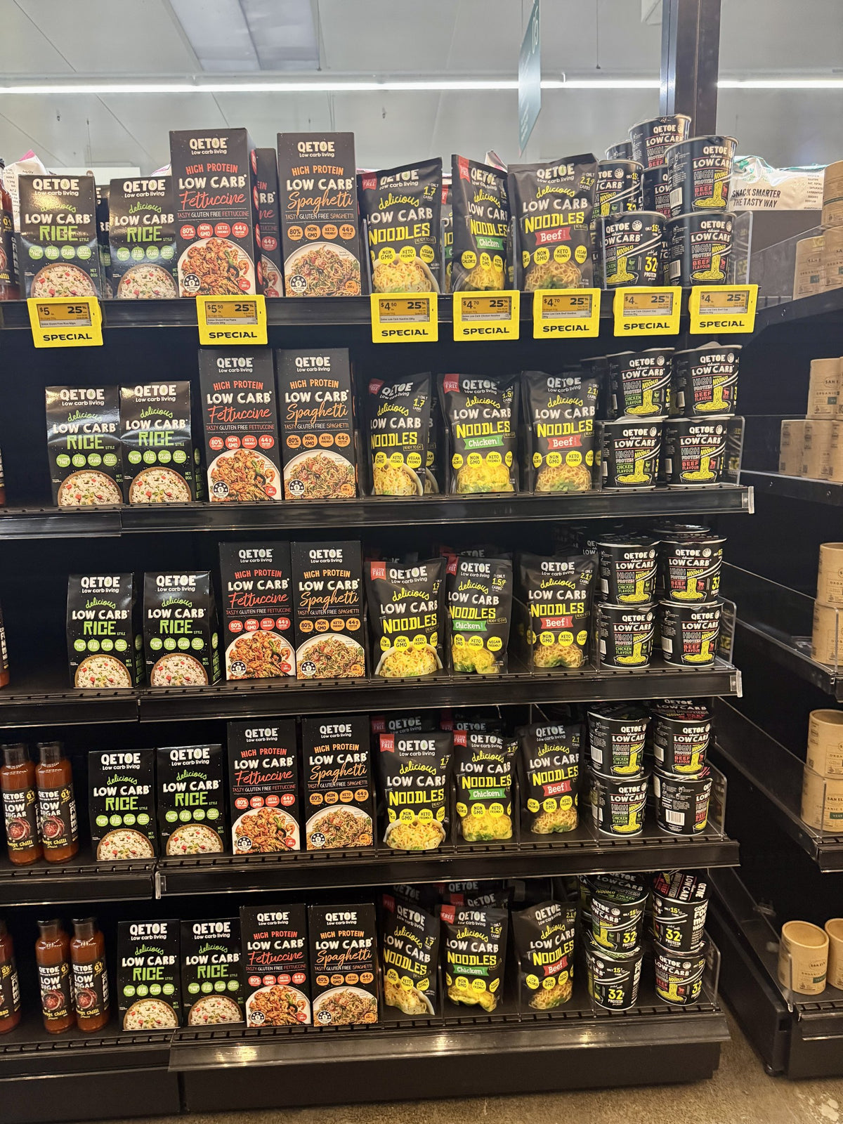 A full bay of Qetoe low carb rice, pasta, noodles, cup noodles and sauces on shelf in a store